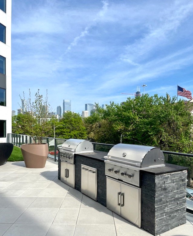 an outdoor barbecue area with two grills and an american flag in the background at Inspire West Town, Chicago 60642