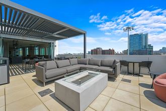 a rooftop patio with a couch and a coffee table and a city in the background