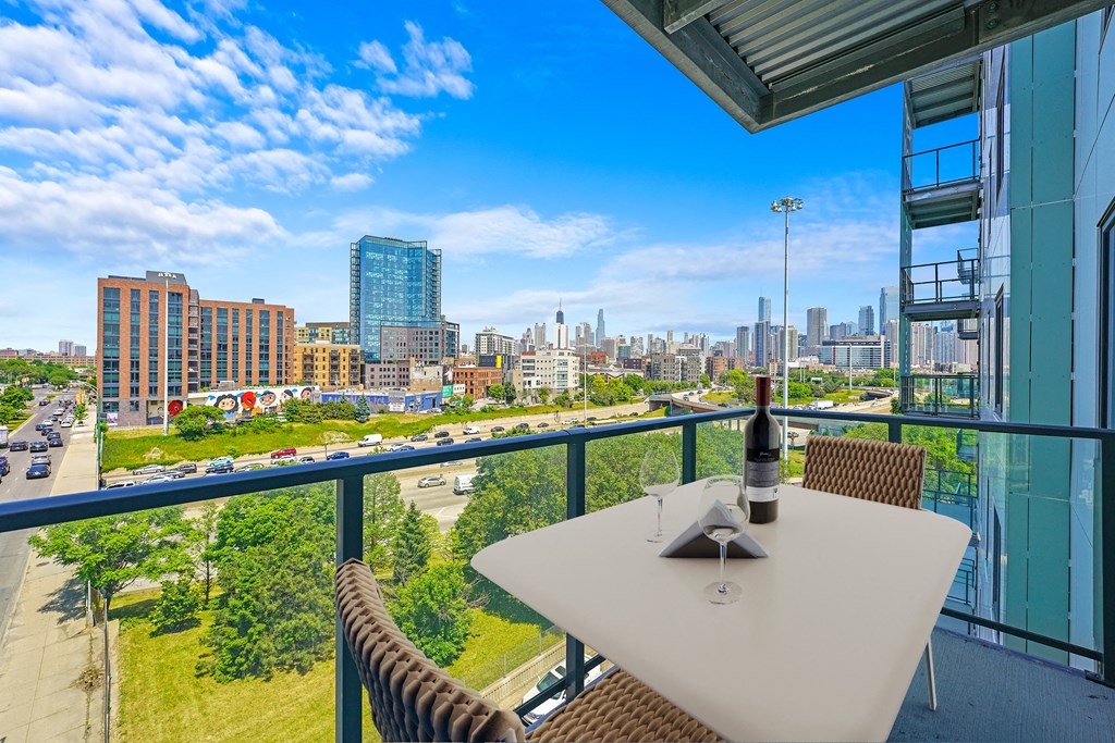 a balcony with a city view and a table with a bottle of wine  at Inspire West Town, CHICAGO, IL, 60642