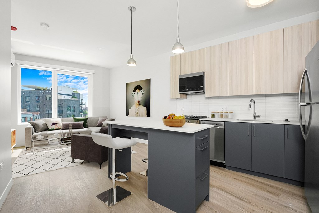 an open kitchen and living room with a gray island and a large window at Inspire West Town, CHICAGO