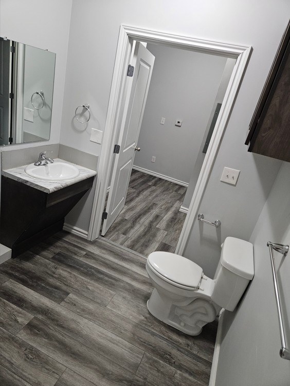 A white toilet sits in a bathroom next to a sink and a mirror.