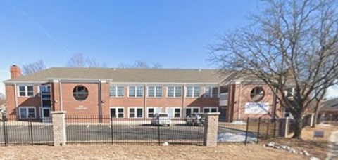 A red brick building with a black fence in front.