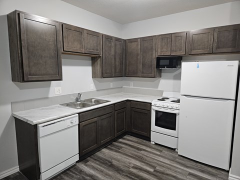 A kitchen with white appliances and brown cabinets.