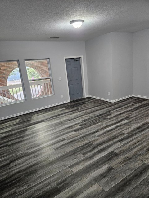 A room with a grey door and a window with a view of a red brick building.