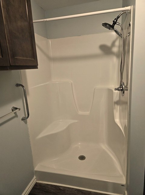 A white bathtub with a shower head and a drain in the middle.
