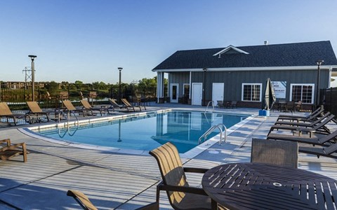 a swimming pool with chairs and tables around it