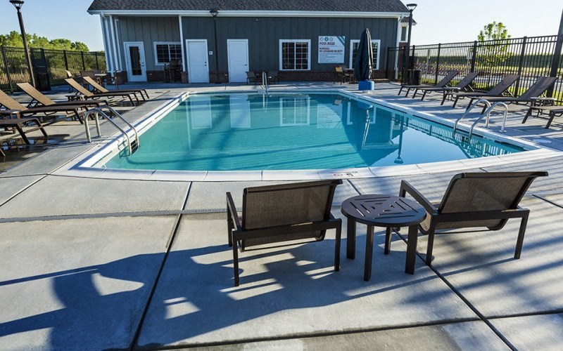 a pool with chairs and a table in front of a building