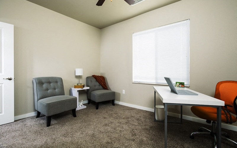 a home office with a desk and chairs and a laptop