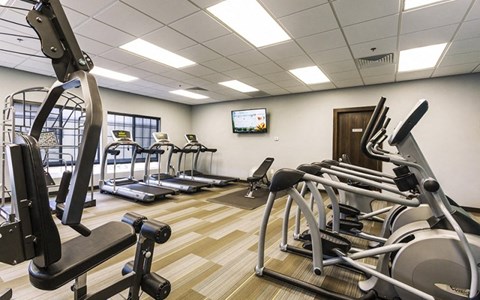 a gym with various exercise equipment and a tv on the wall