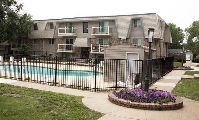 an apartment building with a pool and a fence
