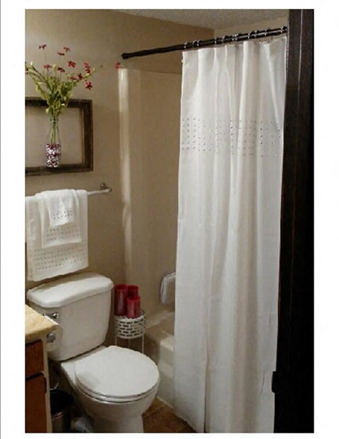 a bathroom with a toilet and a white shower curtain
