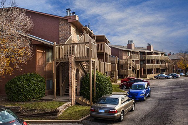 a parking lot with cars in front of an apartment building