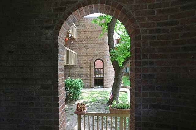 an archway looking into a courtyard with a tree and a brick building