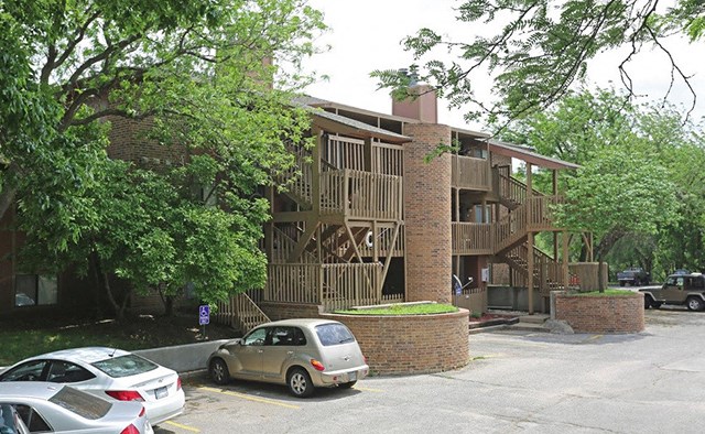 an apartment building with cars parked in a parking lot