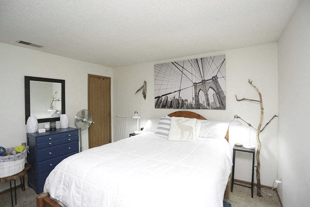 a bedroom with a white bed and a painting on the wall