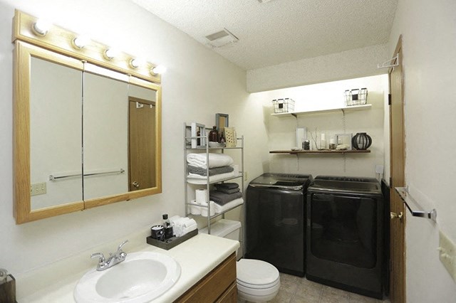 a small bathroom with a washer and dryer and a sink and a mirror