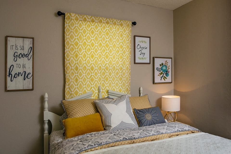 a bedroom with a bed and a yellow curtain and pictures on the wall