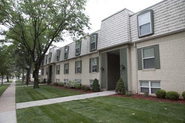 an apartment building with a sidewalk and grass