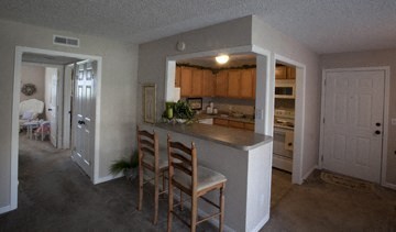 a kitchen with a bar with three chairs