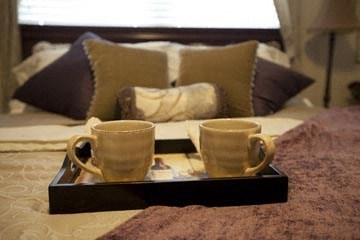 two cups of coffee sitting on a tray on a bed