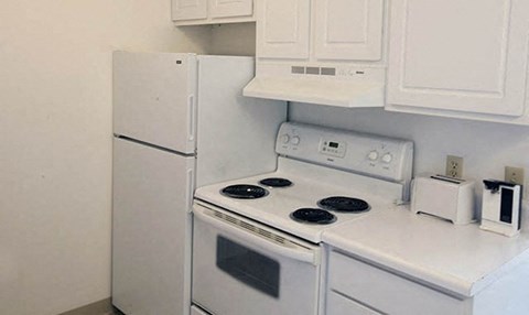 a white kitchen with a stove and a refrigerator