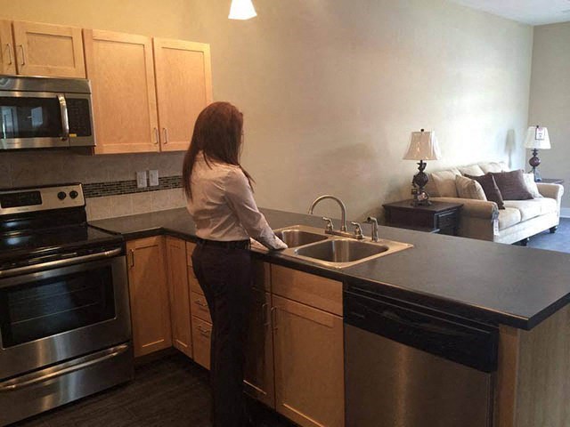 a woman standing in a kitchen with a sink