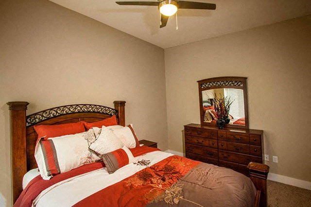 a bedroom with a bed and a dresser and a ceiling fan