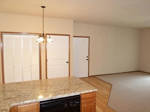 an empty kitchen with a granite counter top and an empty living room