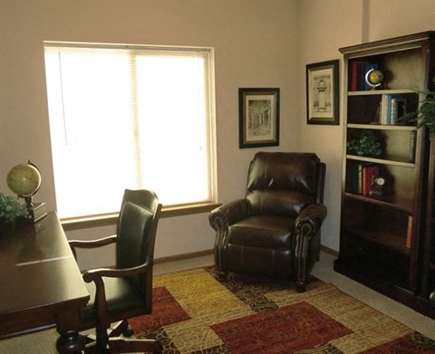 a living room with a leather chair and a desk