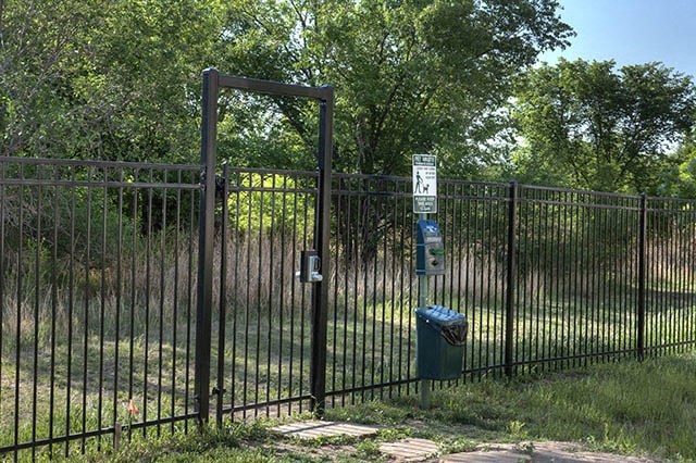 a gate with a trash can in front of a fence