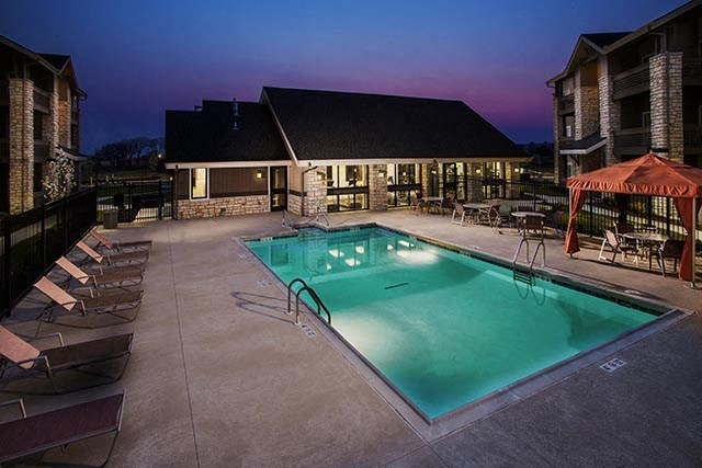 a swimming pool with chairs in front of a building