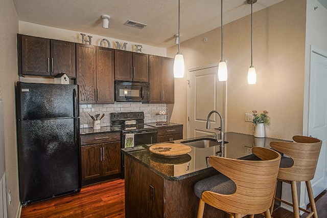 a kitchen with black appliances and a island with chairs