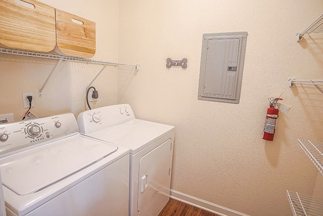 the laundry room has a washer and dryer and a shelf on the wall