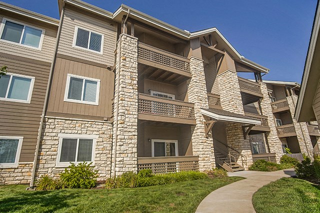 an apartment building with stone pillars and tan and brown walls