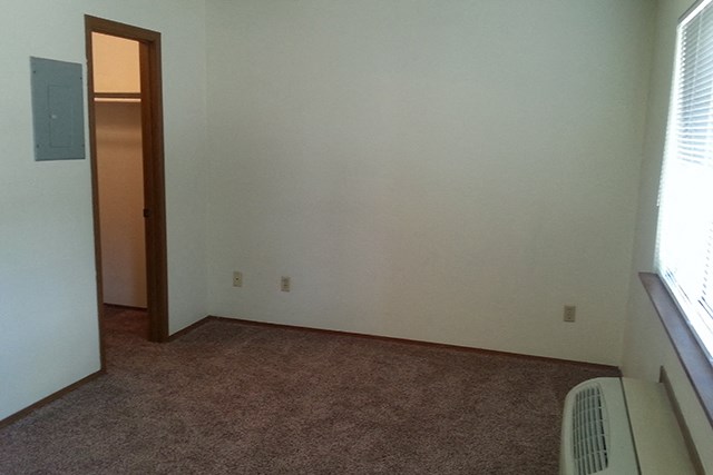 an empty room with a heater and a door to a closet