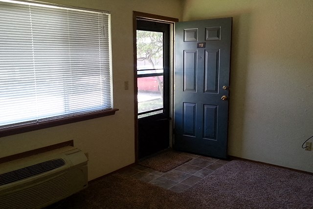 an empty room with a blue door and a window