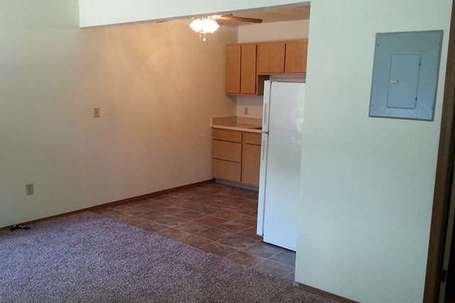 an empty kitchen with a refrigerator and cabinets