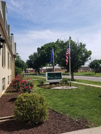 the front yard of a building with flags and a sign