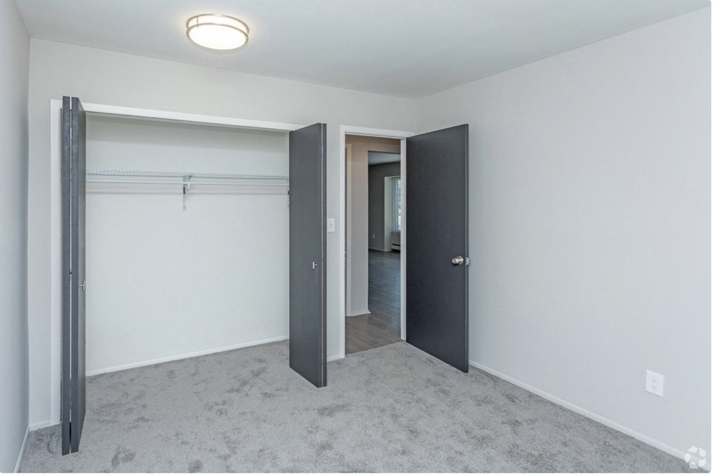 an empty bedroom with a closet and a door to a hallway