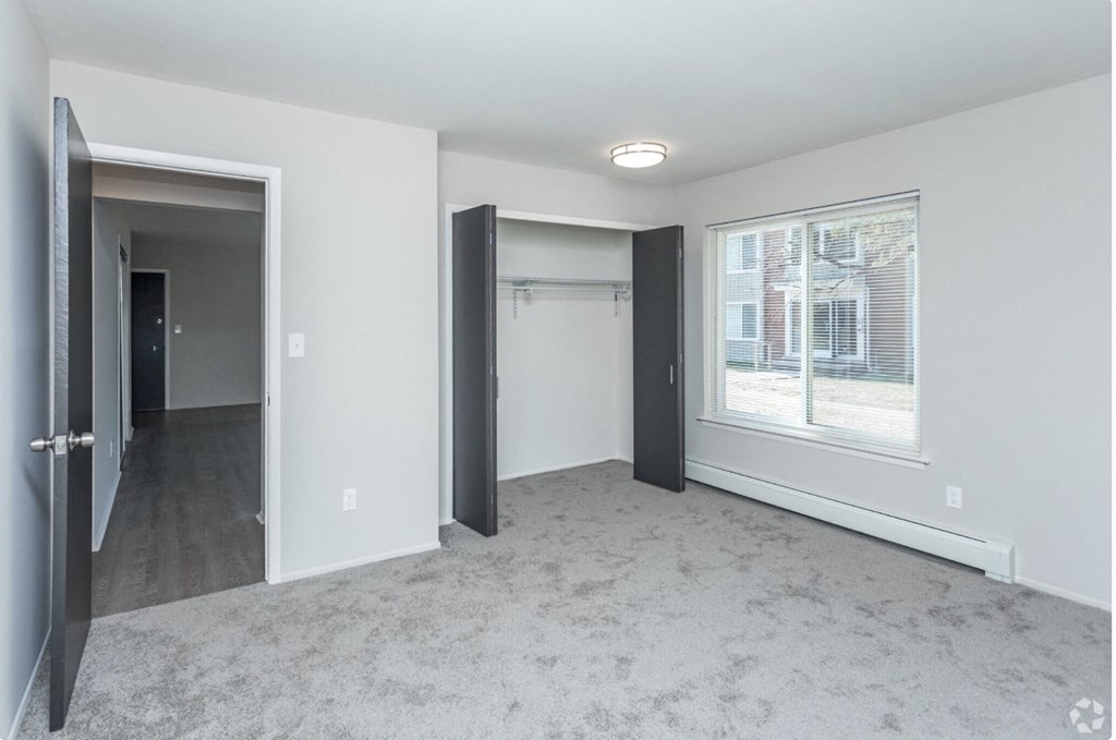 an empty living room with a large window and a door to a closet