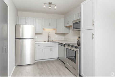 a white kitchen with stainless steel appliances and white cabinets