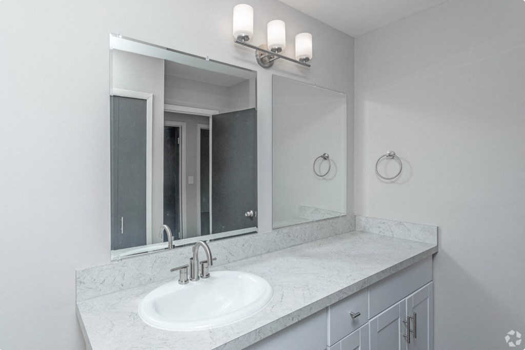 a white bathroom with a sink and two mirrors