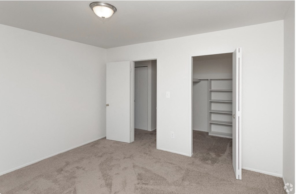 an empty bedroom with a closet and a door to the bathroom