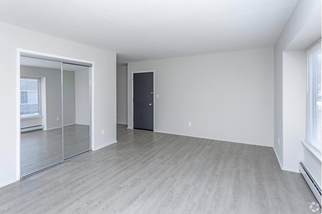 the living room and dining room of an empty apartment with white walls and wood floors