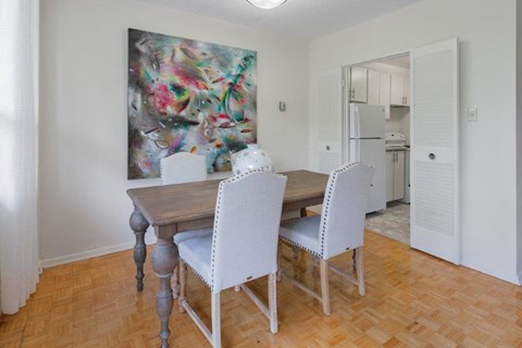 a dining room with a table and chairs and a painting on the wall