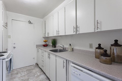a white kitchen with white cabinets and a sink