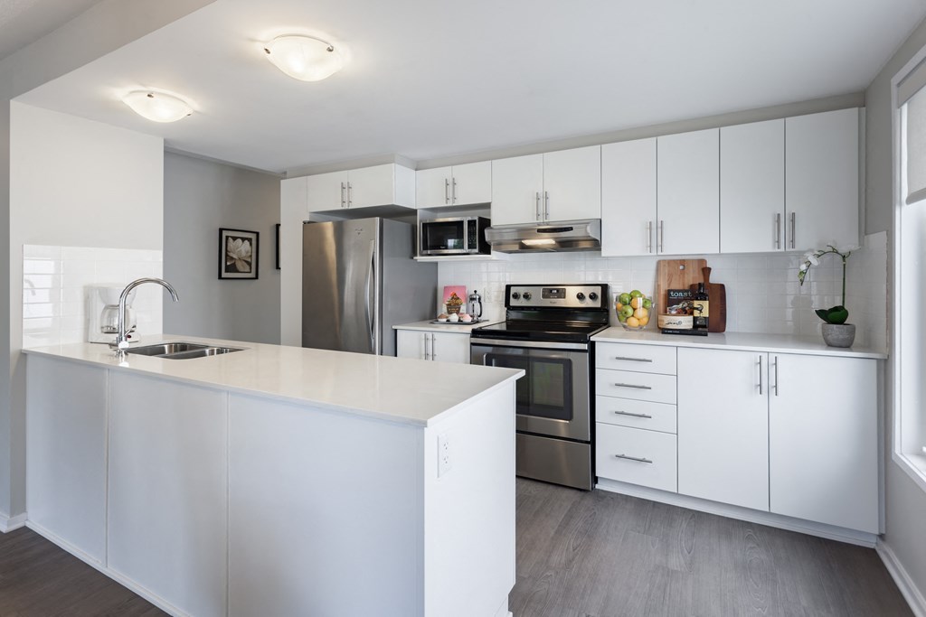 a white kitchen with stainless steel appliances and white cabinets