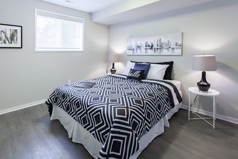 a bedroom with a bed with a black and white comforter and two lamps