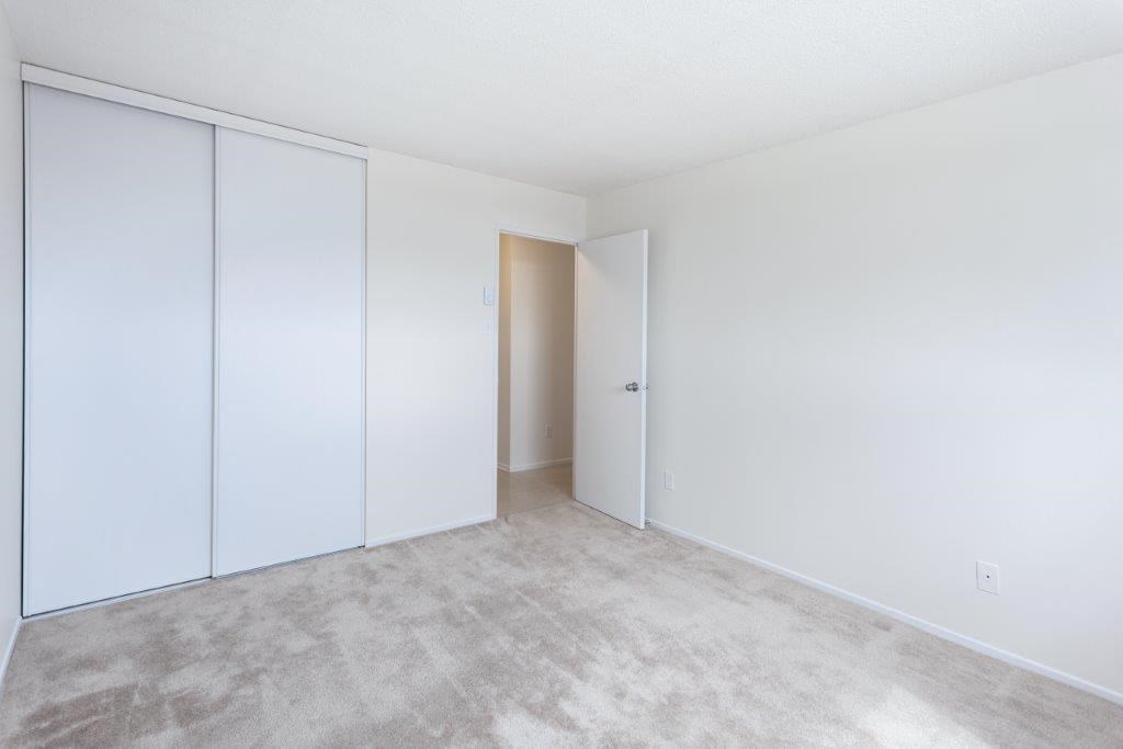 an empty room with white walls and a door to a closet
