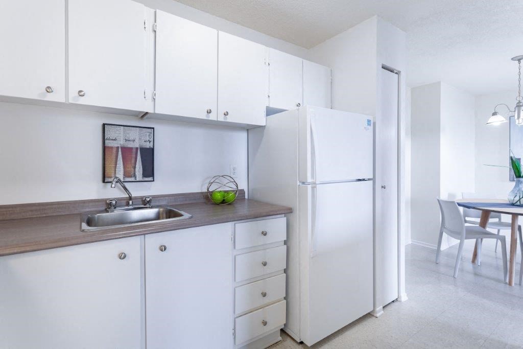 a kitchen with white cabinets and a sink and a refrigerator